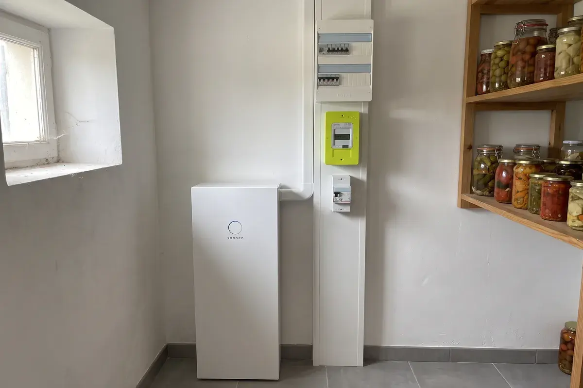 Batterie sonnenBatterie 10 posée au sol d’un cellier, à côté de la gaine technique avec compteur Linky et tableau électrique.