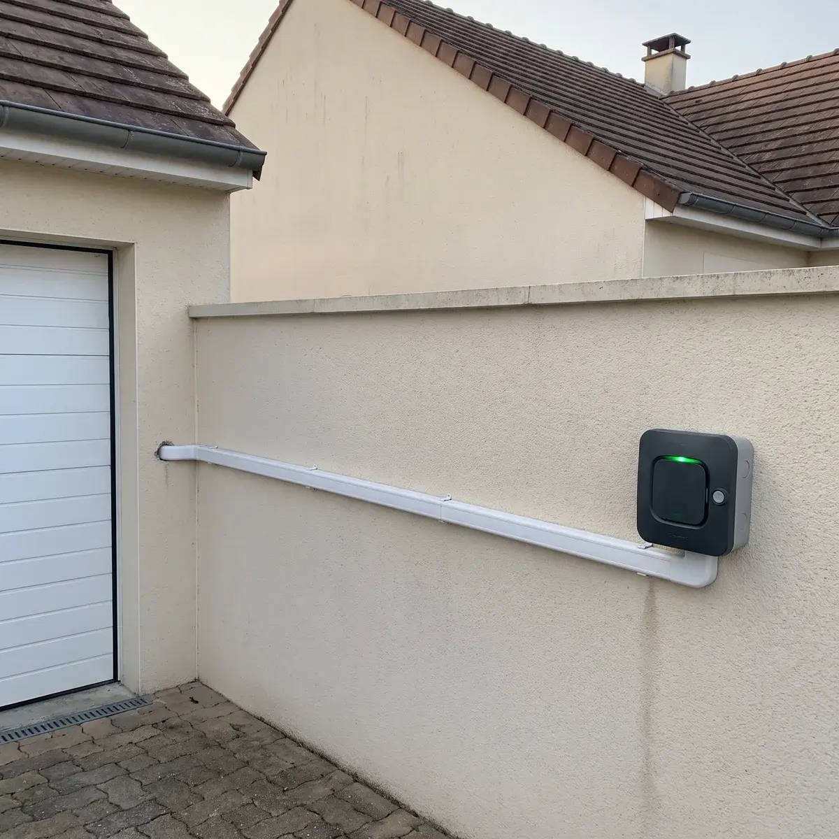 Borne Legrand Green'up Home sur la façade d'un pavillon, alimentée par une longue goulotte depuis le garage.