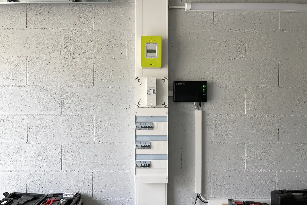 Passerelle Enphase IQ Gateway fixée au mur du garage à côté de la gaine technique avec compteur Linky, disjoncteur de branchement et tableau Legrand.
