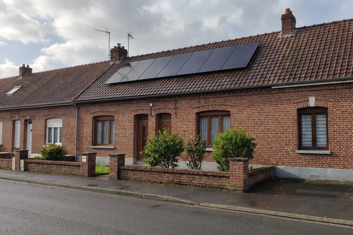 Maison de briques rouges des Hauts-de-France portant une petite rangée de huit modules Voltec Solar TARKA.