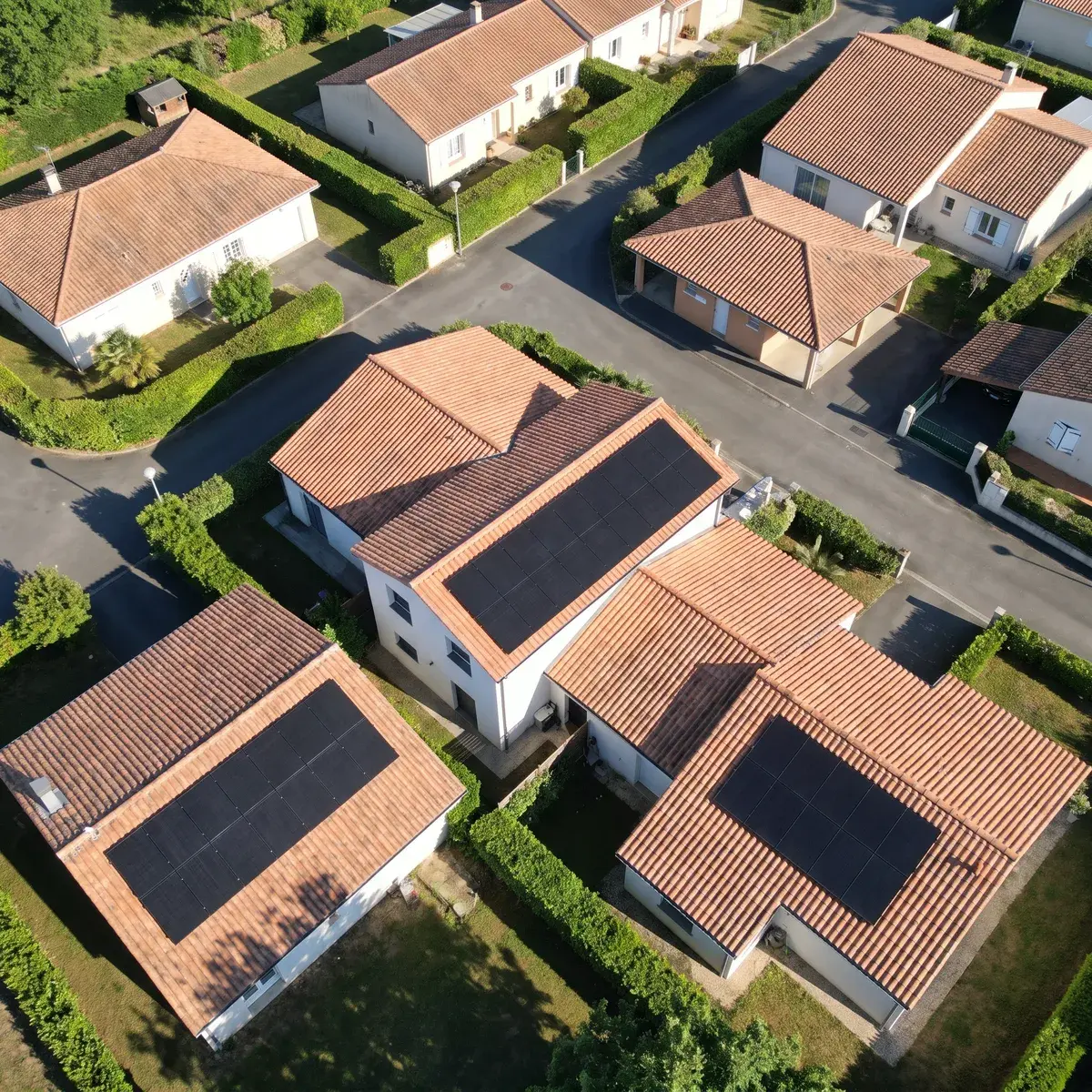 Vue aérienne d'un lotissement de pavillons dont plusieurs toitures portent des modules DualSun FLASH.