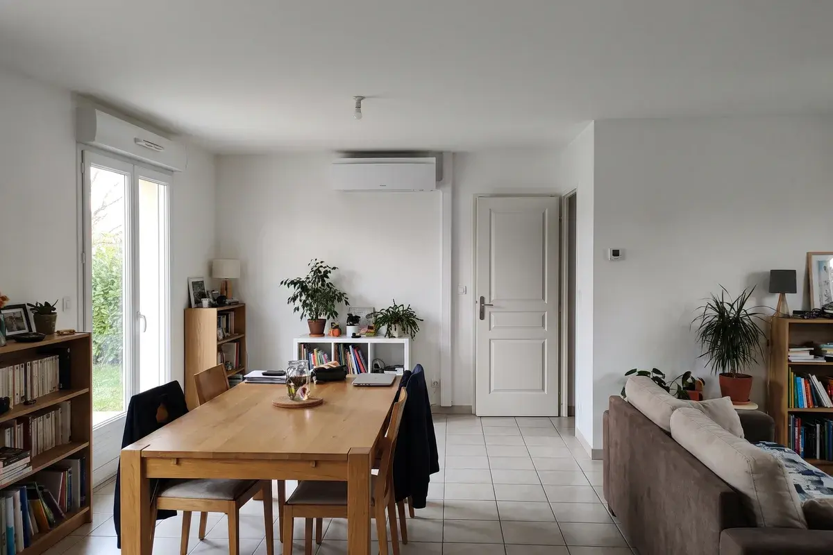 Une seule unité murale Daikin Emura 3 au fond du séjour ouvert d’un pavillon des années 1990, avec coin repas et canapé.