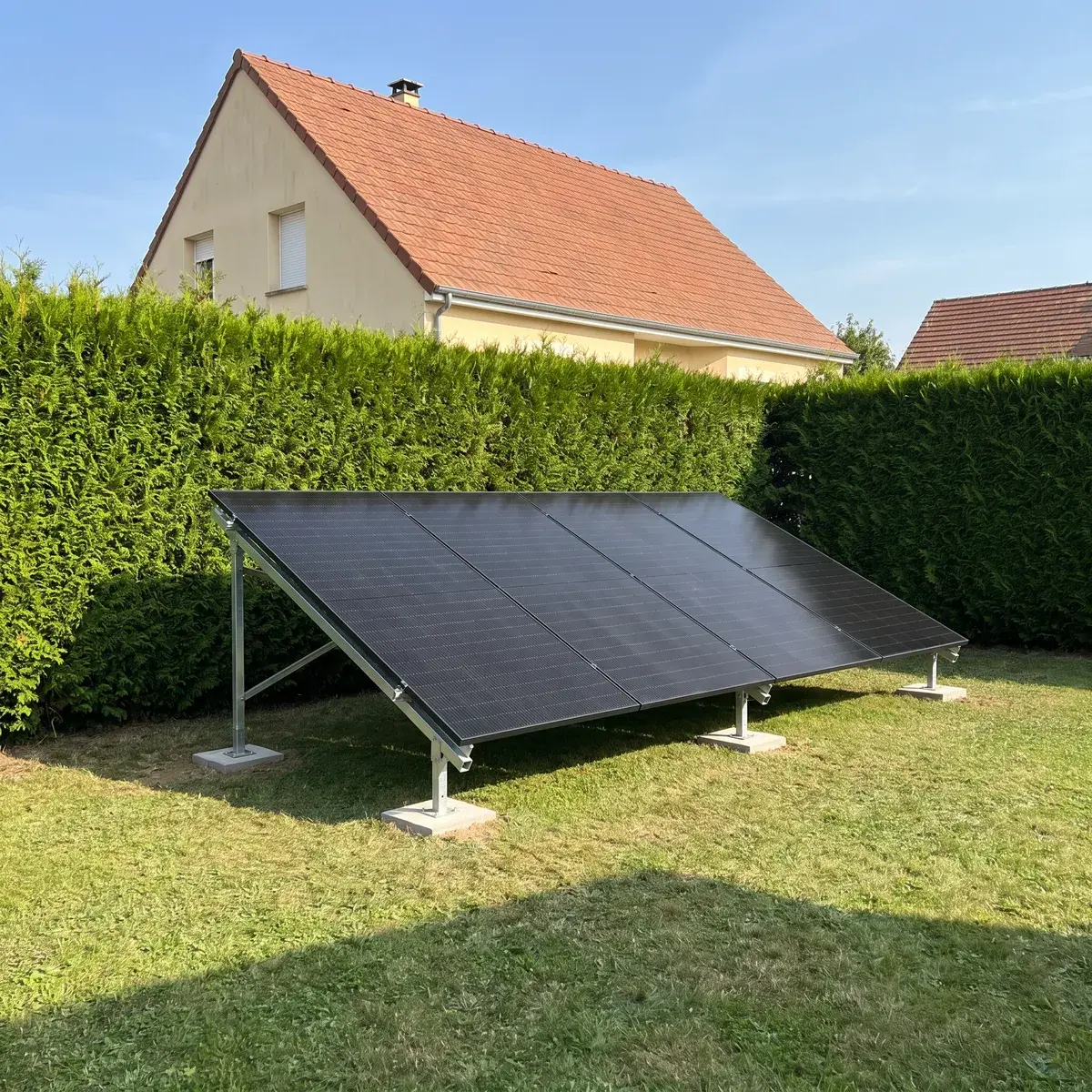 Six modules DualSun FLASH sur un châssis au sol au fond du jardin d'un pavillon.