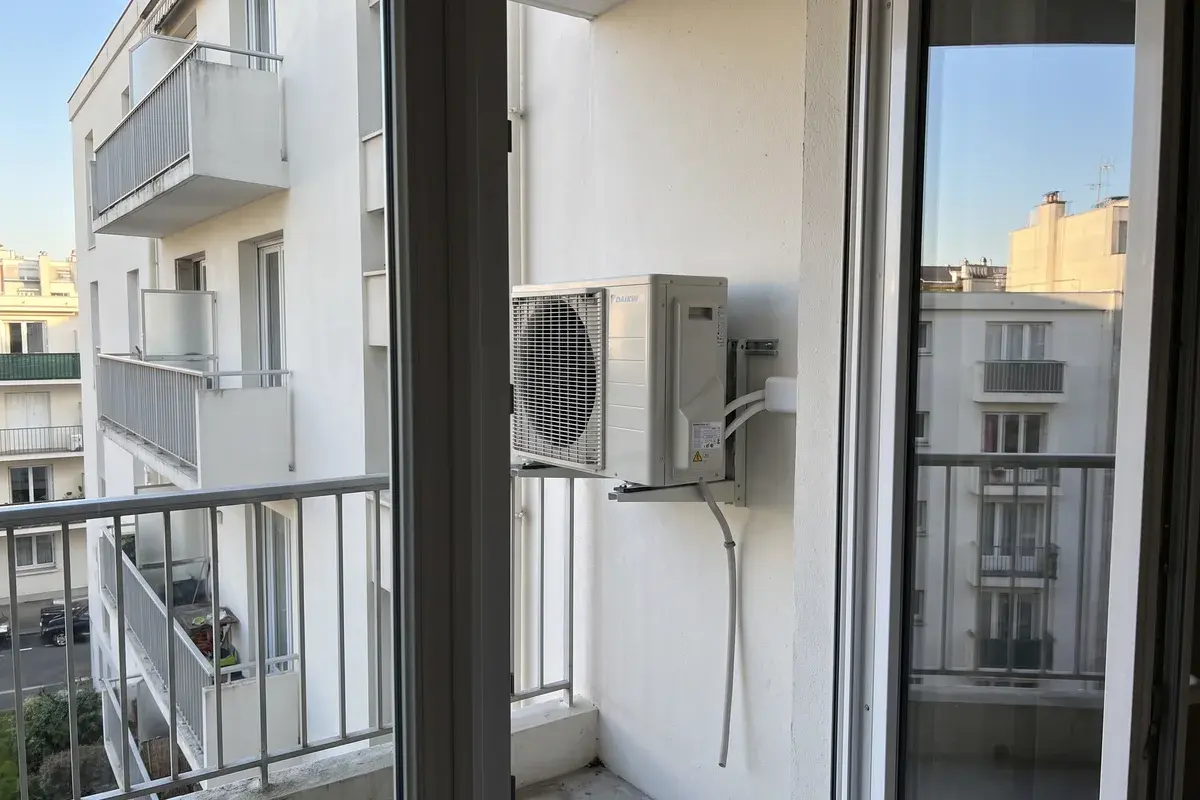Unité extérieure Daikin Perfera fixée sur console au bout du balcon d’un immeuble des années 1970.