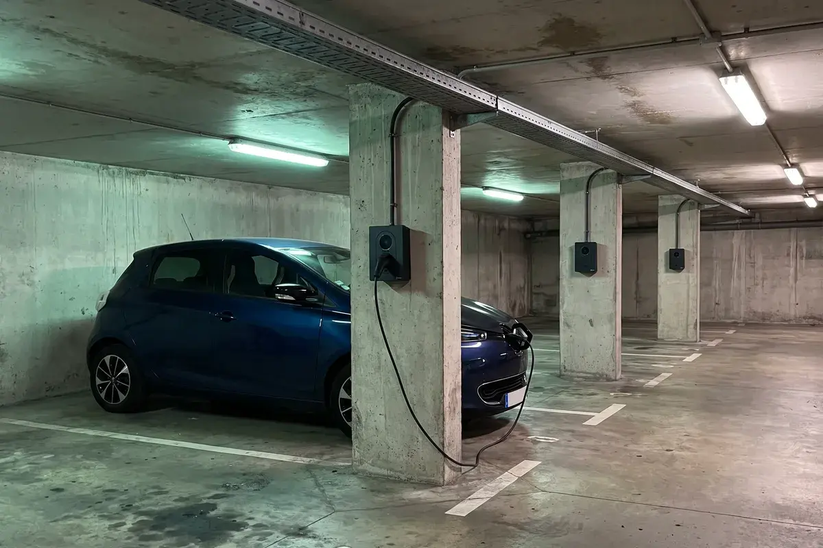 Parking souterrain d’une copropriété avec des bornes Zaptec Go 2 fixées aux piliers, l’une branchée sur une Renault Zoe.