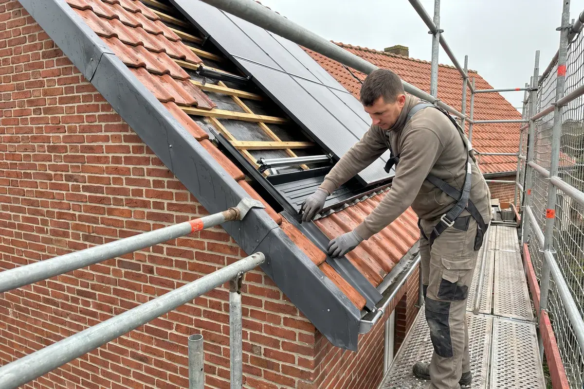 Un couvreur pose l’abergement latéral d’un système d’intégration GSE In-Roof sur une toiture en tuiles d’une maison en briques du Nord.