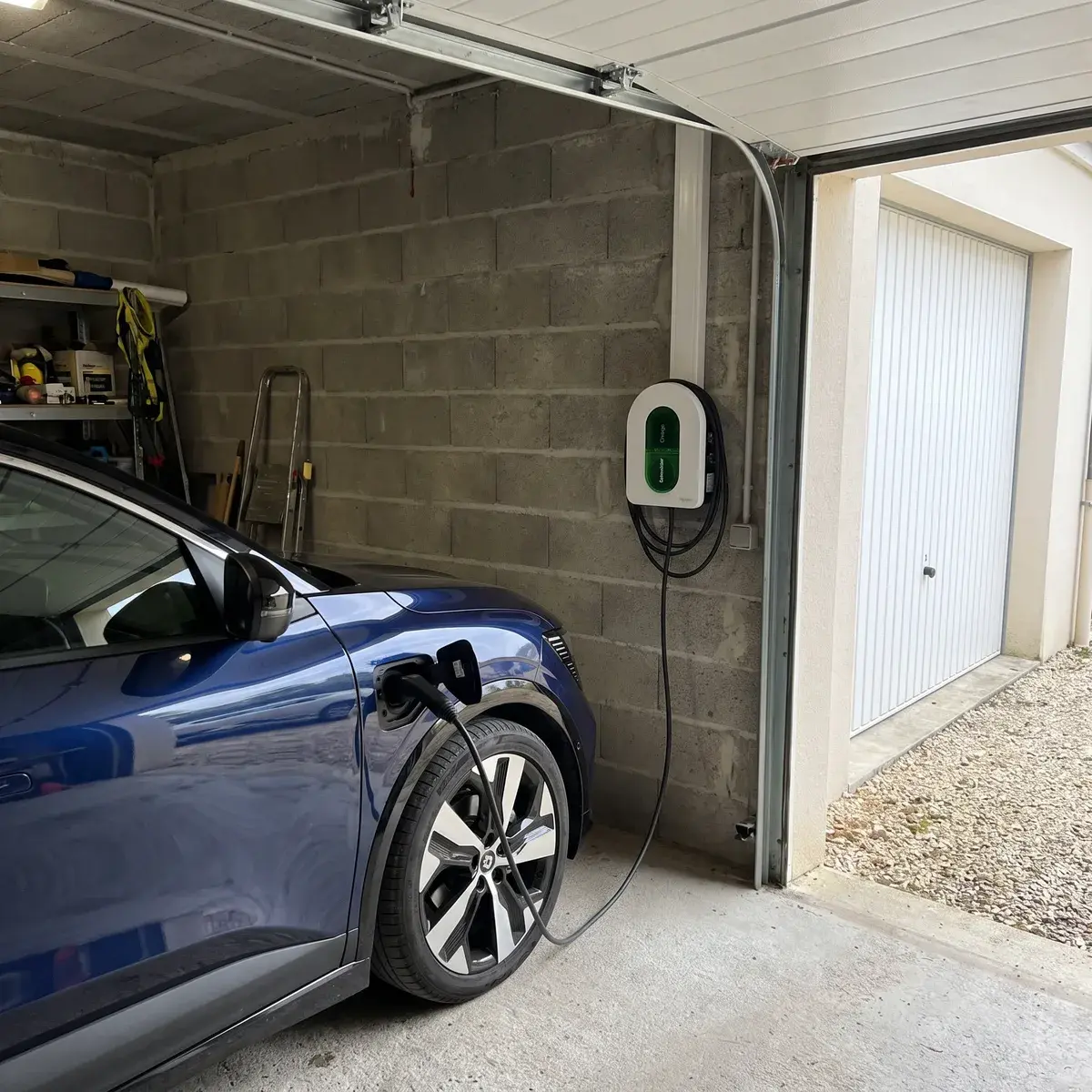 Borne Schneider Charge fixée au mur d'un garage en parpaing, raccordée à une Renault Mégane E-Tech.