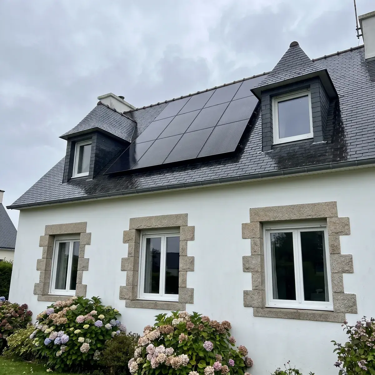 Maison néo-bretonne couverte d'ardoise équipée de modules noirs AIKO NEOSTAR.