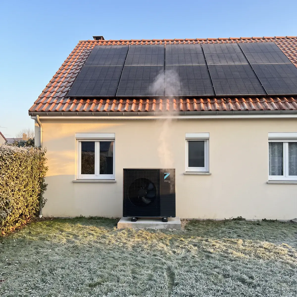 Matin de gel : pompe à chaleur Daikin Altherma 4 H au pied d'un pavillon équipé de panneaux solaires.