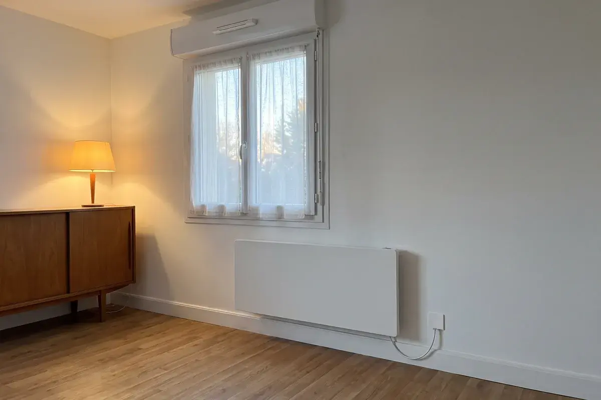 Radiateur électrique Thermor Équateur 5 fixé sous la fenêtre du séjour d’un pavillon des années 1970 chauffé à l’électricité.