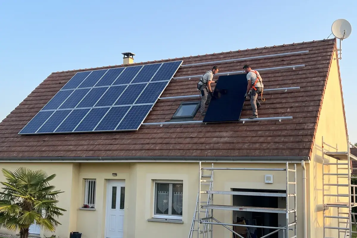 Deux couvreurs ajoutent des modules à côté d’une installation existante.