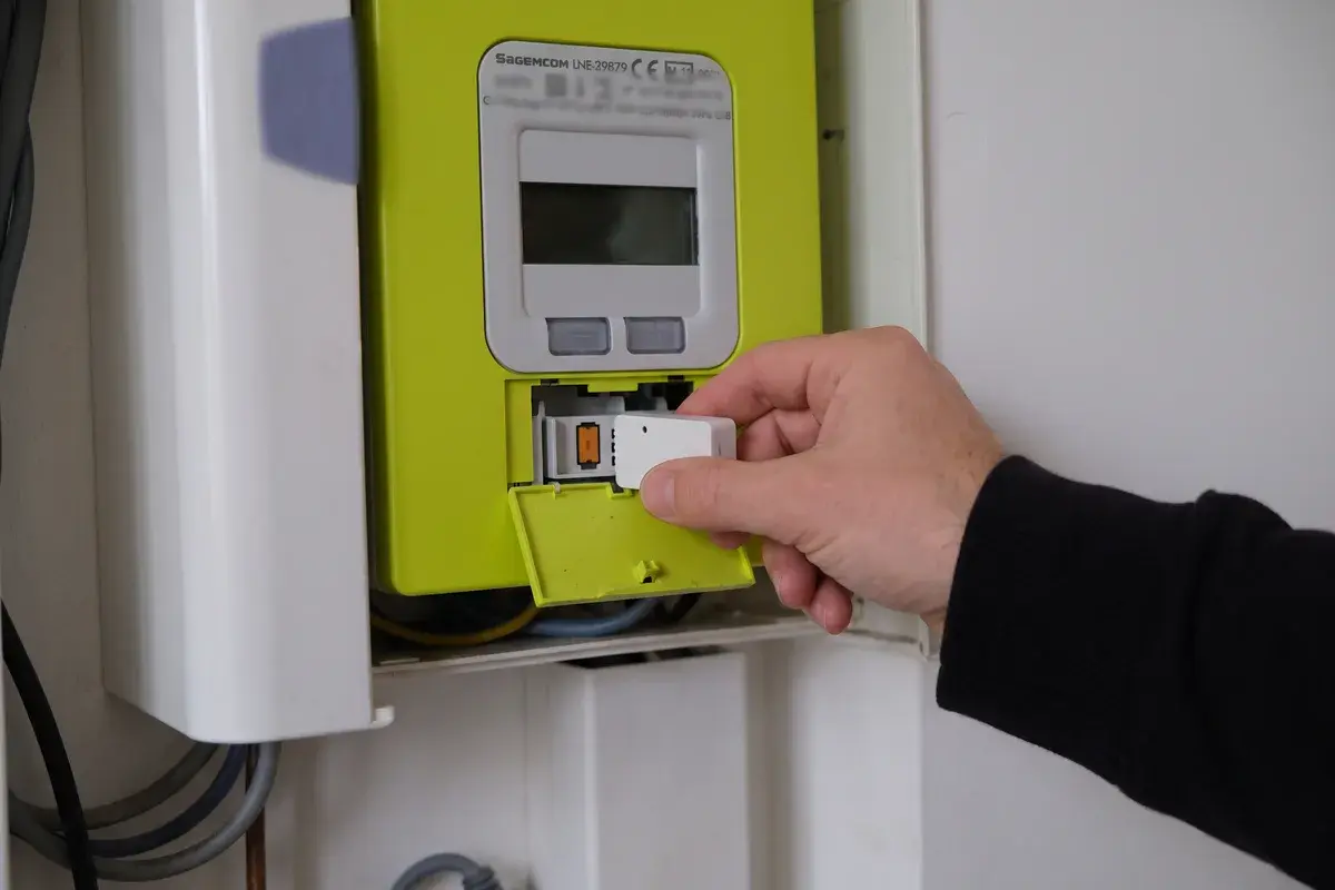 Une main enfiche un module LiXee ZLinky_TIC dans les bornes de téléinformation, sous le cache inférieur d’un compteur Linky.